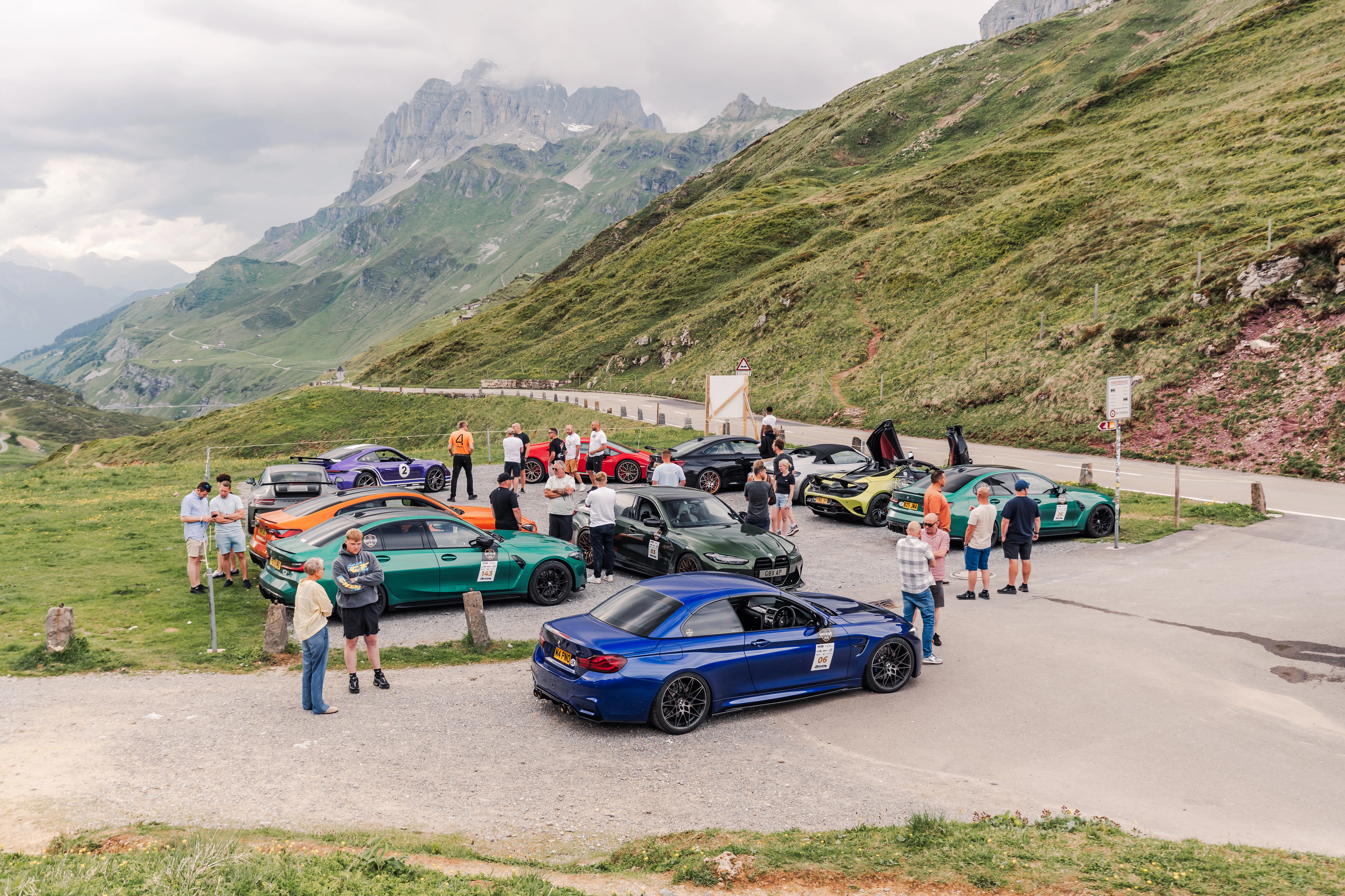Driven+ customers and their sports cars gathered beside a mountain pass